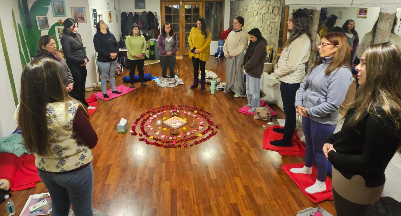 Mujeres participando en una ceremonia de Sanación de Útero y Rito del Útero con las manos sobre su propio útero.